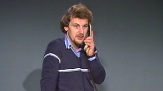 Ein Archivbild des Fernsehmoderators Jörg Wontorra, der ein Telefon in der Hand hält.