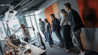 Fünf Menschen stehen im Bremen-Vier-Studio und hören Moderatorin Franziska Henke zu