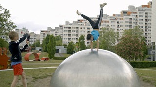 Zwei Kinder in Sportkleidung vor Hochhauskomplex