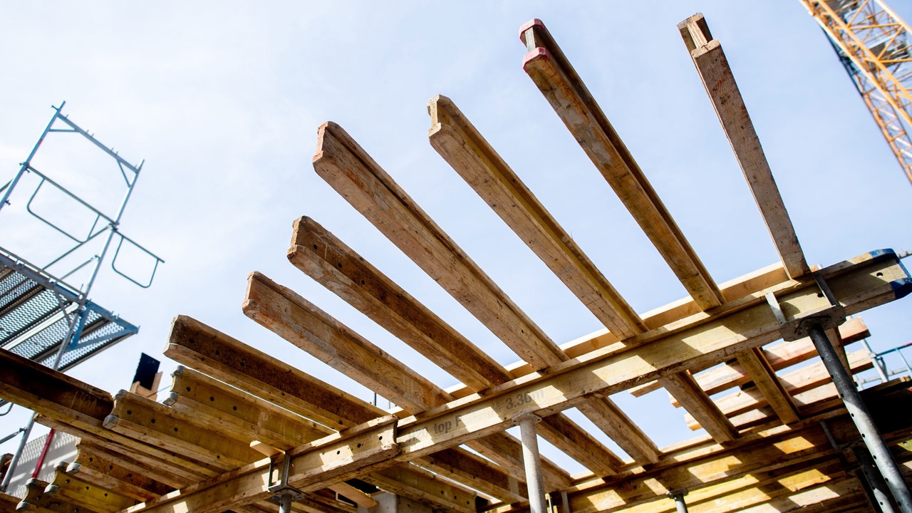 Eine Holzkonstruktion für den Bau einer weiteren Etage aus Stahlbeton steht auf einer Baustelle.