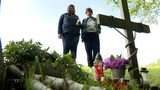 Zwei Frauen stehen vor einem Kreuz am Straßenrand
