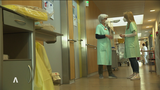 Zwei Frauen in grünen Kitteln in einem Krankenhausflur