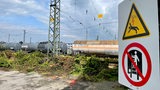 Güterwaggons auf den Gleisen, daneben ein Warnschild
