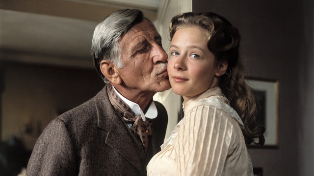 Szene aus dem Film Sommer in Lesmona: Ein älterer Herr gibt einer jüngeren Dame ein Küsschen auf die Wange.