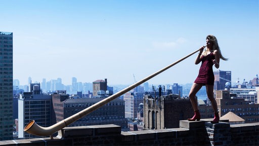 Eliana Burki mit Alphorn über den Dächern von New York