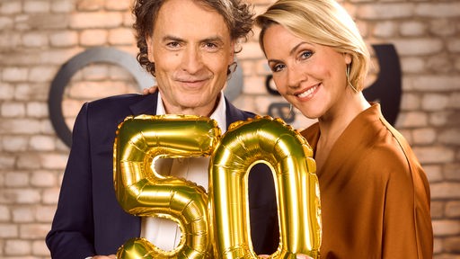 Giovanni di Lorenzo und Judith Rakers halten lachend eine goldene 50 hoch