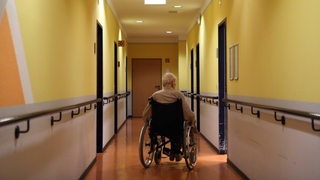 Ein Rollstuhlfahrer auf dem Flur eines Altenheims.