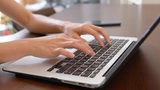 Eine Frau schreibt auf einer Laptop-Tastatur (Symbolbild)