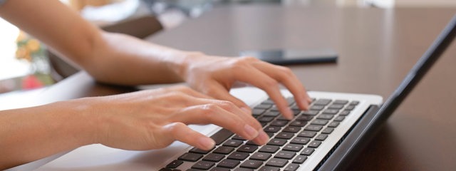Eine Frau schreibt auf einer Laptop-Tastatur (Symbolbild)