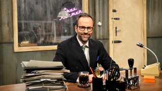 Kurt Krömer sitzt am Schreibtisch seiner Sendung "Chez Krömer"