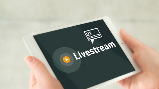 Zu sehen ist ein Tablet mit der Aufschrift "Livestream" und stilisierten Untertiteln.