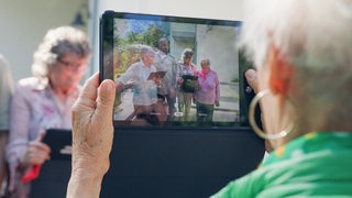 Eine Frau macht mit einem Tablet ein Foto von einer Gruppe
