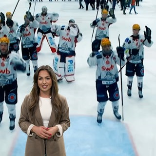 Eine Frau mit dunklen Haaren vor einem Foto eines Eishockeyfelds.