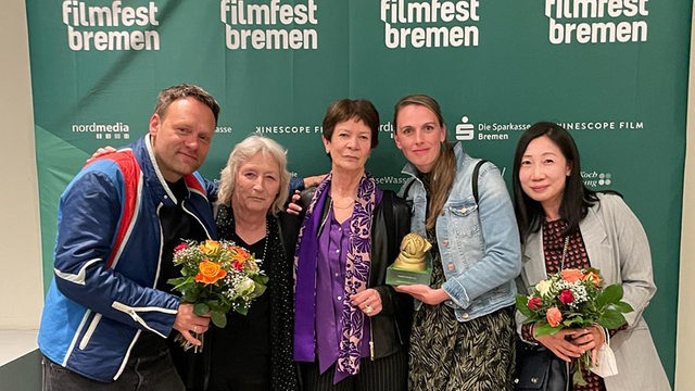 Das Film-Team vor einem Filmfest-Bremen-Plakat