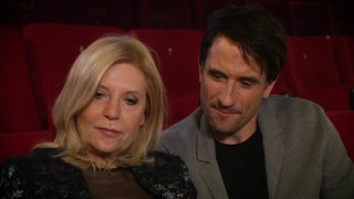 Die Tatort- Schauspieler Sabine Postel und Oliver Mommsen, die nebeneinander sitzen.