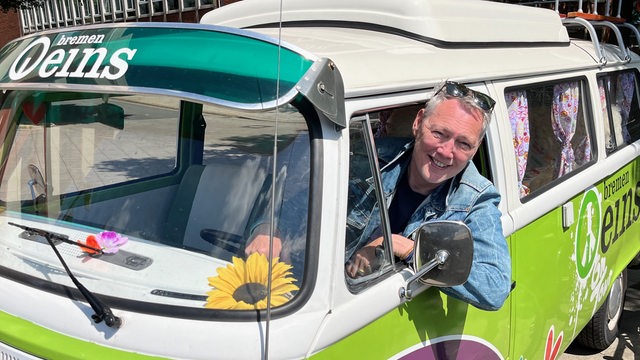 Bremen Eins Moderator Dirk Böhling schaut aus dem Fahrerfenster eines grünen VW-Bullis