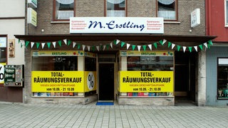 Ladenansicht und Schaufenster mit Beklebung "Total-Räumungsverkauf"