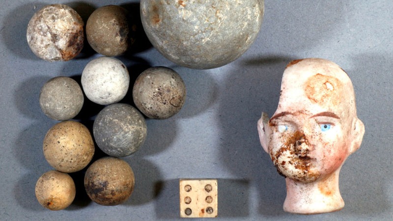 Steinkugeln, ein Würfel und Reste eines Puppenkopfes