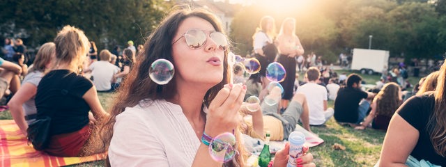 Junge Frau lässt Seifenblasen steigen auf dem Summer-Sounds-Festival