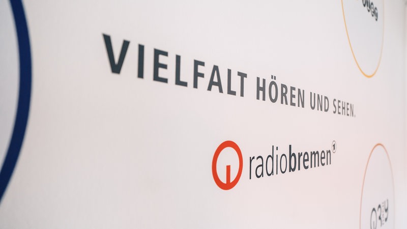 Auf einer Wand steht Vielfalt hören und sehen mit den verschiedenen Logos von Radio Bremen